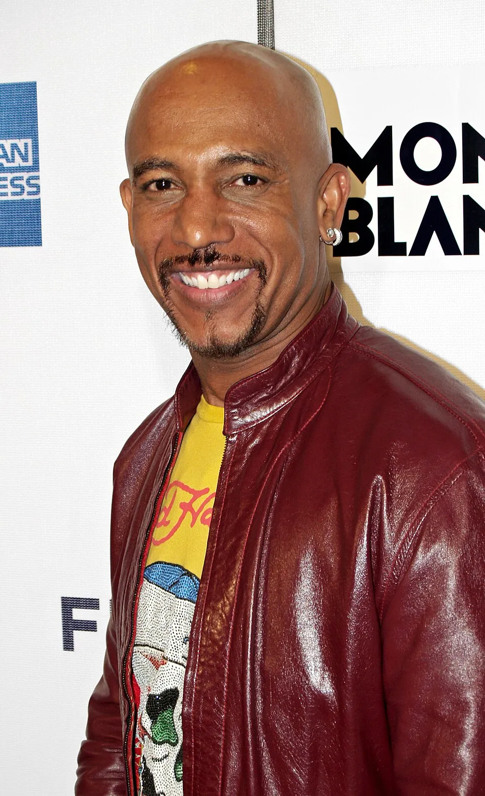 Montel Williams smiling in a red leather jacket.