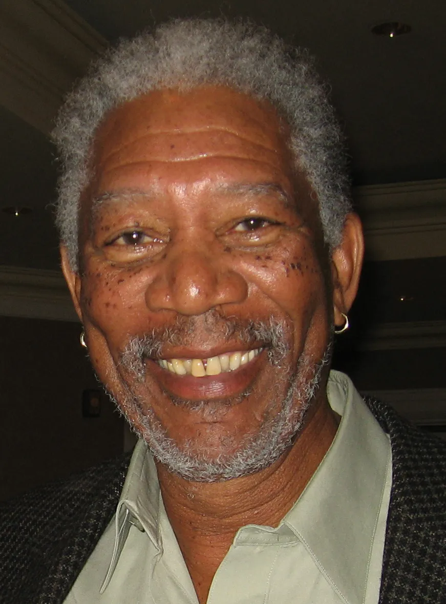 Morgan Freeman smiling warmly in a collared shirt and jacket.
