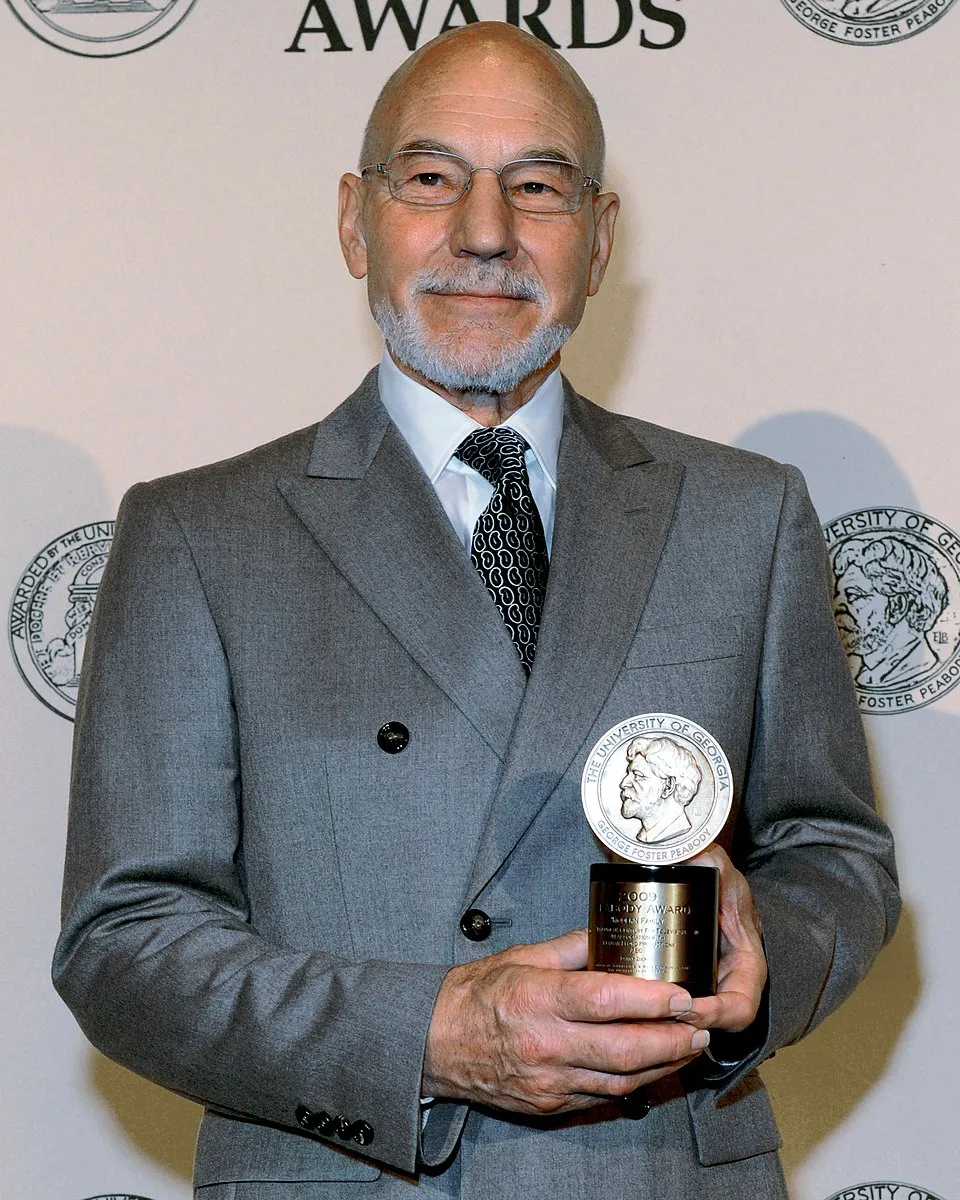 Sir Patrick Stewart smiling in a gray suit.