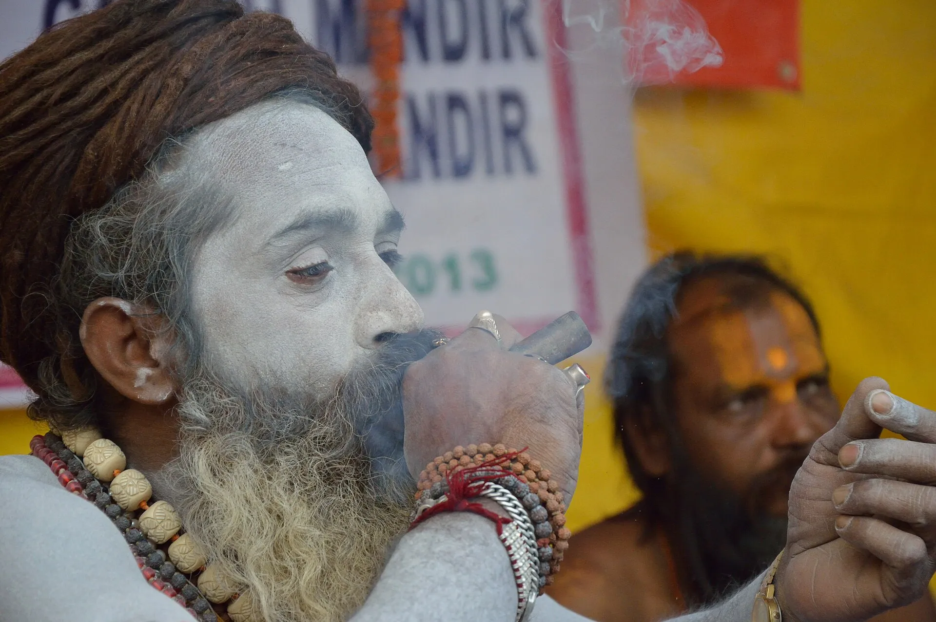 A Naga sadhu wrapped in marigold garlands smokes ganja at the Gangasagar Fair transit camp in Kolkata.
