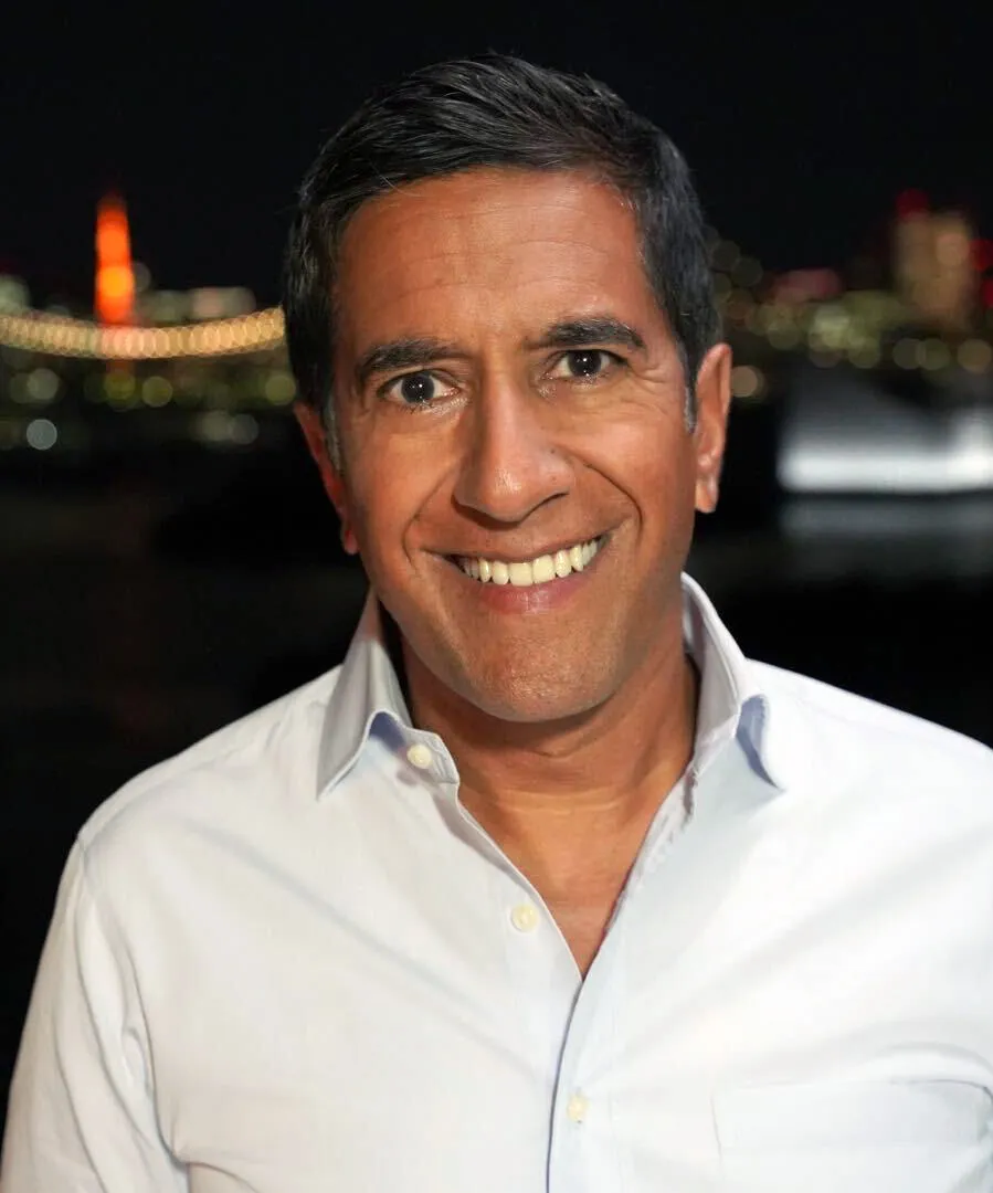 Dr. Sanjay Gupta smiling in an open-collared white shirt.